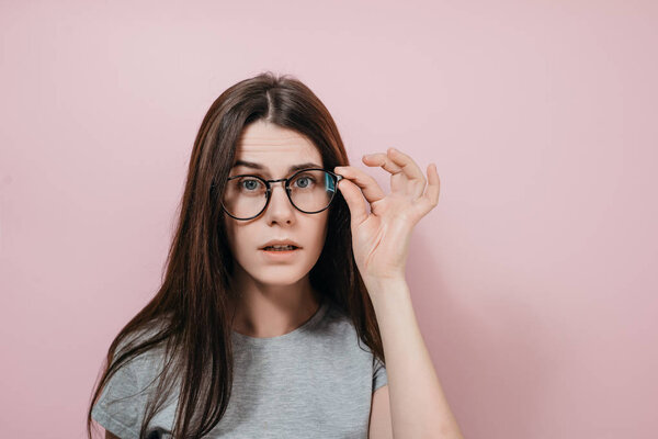 Крупный план портрета молодой женщины, хмурящейся озадаченной учительницей, выглядящей серьезно, имеющей внимательный взгляд на что-то. Красивая женщина в очках смотрит в камеру
.