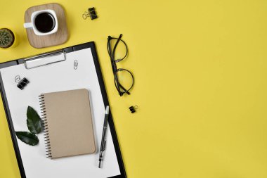 Ofis Resepsiyon çalışma alanı boş klibi kurulu, büro malzemeleri, kalem, kaktüs, yaprak yeşil, kahve fincanı bir ahşap stand ve Sarı zemin üzerine gözlük ile. Düz yatıyordu, en iyi görünümü blog kavramı