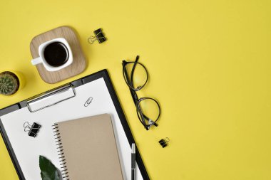 Ofis Resepsiyon çalışma alanı boş klibi kurulu, büro malzemeleri, kalem, kaktüs, yaprak yeşil, kahve fincanı bir ahşap stand ve Sarı zemin üzerine gözlük ile. Düz yatıyordu, en iyi görünümü blog kavramı