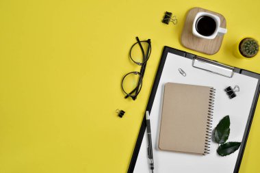 Ofis Resepsiyon çalışma alanı boş klibi kurulu, büro malzemeleri, kalem, kaktüs, yaprak yeşil, kahve fincanı bir ahşap stand ve Sarı zemin üzerine gözlük ile. Düz yatıyordu, en iyi görünümü blog kavramı