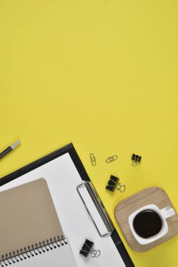 Çalışma alanı boş klibi kurulu, büro malzemeleri, kalem, kahve fincanı bir ahşap stand ve Sarı zemin üzerine gözlük ile alay. Düz yatıyordu, en iyi görünümü