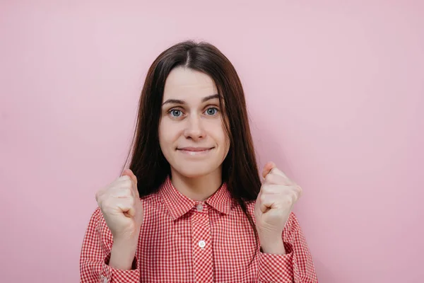 Gioioso successo giovane femmina europea raggiunge gli obiettivi, facendo gesto di vittoria in studio. Felice vincitore femminile stringe pugni, gioisce trionfo sul lavoro . — Foto Stock