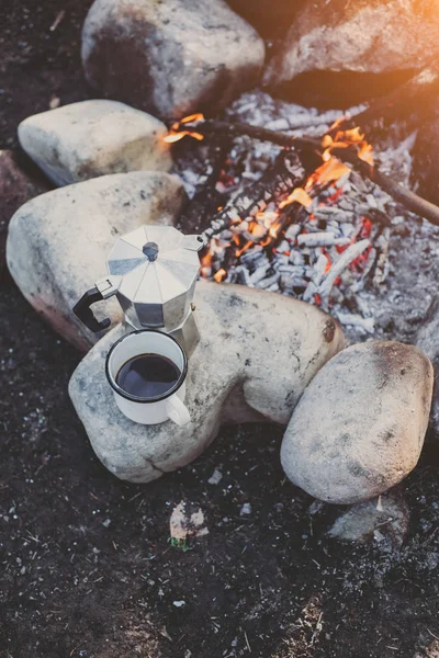 Xícara de café quente e cafeteira perto de fogueira. Conceito aventura férias ativas ao ar livre. Campo de férias — Fotografia de Stock