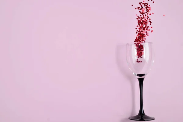 Bicchieri da vino Clinking con spruzzi di coriandoli a forma di cuore rosso su sfondo rosa. Vista aerea, copiare spazio. Concetto vacanza e compleanno — Foto Stock