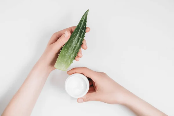 Vista ritagliata delle mani femminili con crema biologica e foglia di aloe vera su sfondo bianco. Layout piatto, vista dall'alto, spazio di copia, stile minimale. Concetto bellezza . — Foto Stock