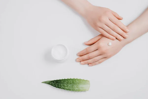 Imagen creativa de la mujer hidratando su mano con crema orgánica en las manos, hoja de aloe vera y recipiente de crema sobre fondo blanco. Estilo minimalista. Concepto plantilla blog femenino, concepto de belleza — Foto de Stock