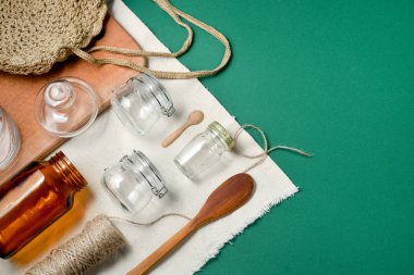 Plastik ücretsiz, sıfır atık alışveriş ve yaşam. Meyve veya sebze, keten masa örtüsü, cam kavanoz, fincan ve yeşil arka planda ahşap kaşık için yeniden kullanılabilir, geri dönüştürülmüş, ev yapımı çanta üretmek.