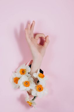 El gösterisi bir jest gösteriyor Tamam, tamam, çiçeklerle pembe kağıt bir delik üzerinden görülebilir. Vücut dili kavramı.