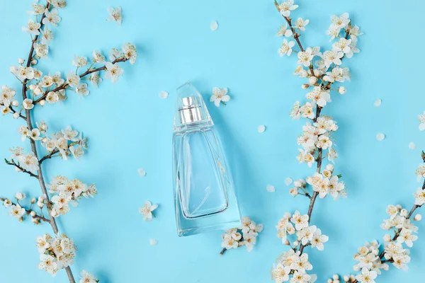 Flaska med kvinnlig parfym och Blomkvist körsbär på blå bakgrund. Parfymeri, kosmetika. Skönhet blogg layout. Vår minimala koncept. Platt Lay, uppifrån, kopiera utrymme. — Stockfoto