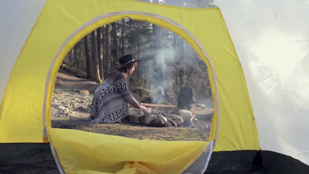 野营妇女把热咖啡倒在篝火和帐篷旁边 早晨在山区旅行 — 图库视频影像