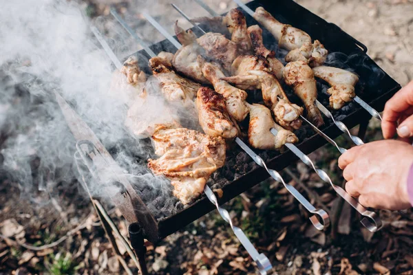 Foto de primer plano de la parrilla de barbacoa con carne de pollo al aire libre en la hora de verano. Hombre cocinando comida en la naturaleza. Concepto aventura activo vacaciones al aire libre —  Fotos de Stock