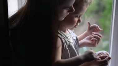 Mutlu anne ve çocuk kızı pencerenin yanında evde eğlenmek oynarken, genç anne ve çocuk birlikte gülerek zaman harcama keyfini çıkarın