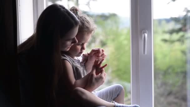 快乐的妈妈和孩子的女儿玩玩在窗口附近的家的乐趣 年轻的妈妈和孩子享受花时间一起笑 — 图库视频影像