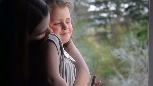 快乐的年轻母亲和女儿亲吻和拥抱 一起在家的大窗旁休息 家庭概念 — 图库视频影像