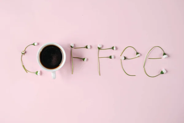 "Káva "je vyrobena z heřmánových květů a kávového šálku na růžovém pozadí. Tvůrčí koncept. Plochý, pohled shora, kopírovat prostor — Stock fotografie