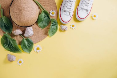Gezgin aksesuarları, tropikal yaprak, şapka, Ayakkabı ve sarı arka plan üzerinde deniz kabuğu. Seyahat tatil konsepti. Yaz geçmişi. Düz yatıyordu, üst görünüm, kopya alanı