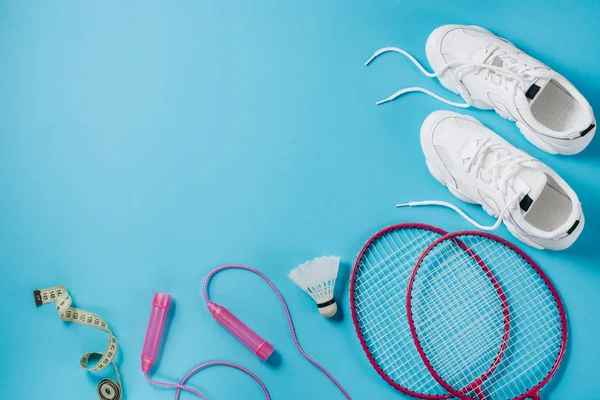 Sport uitrusting. Shuttle en badminton racket, springtouw, sneakers en meetlint op blauwe achtergrond. Fitness, sport en gezond lifestyle concept. Platte lay, bovenaanzicht, kopieerruimte — Stockfoto