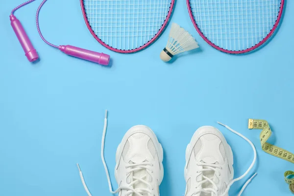 Sport platt låg med badmintonbollen och badmintonracket, hopprep, sneakers och måttband på blå bakgrund. Fitness, sport och hälsosam livsstil koncept. — Stockfoto