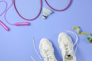 Spor düz mekiği ve badminton raket ile yatıyordu, ip atlama, spor ayakkabıları ve mor arka planda ölçüm bandı. Fitness, spor ve sağlıklı yaşam konsepti.
