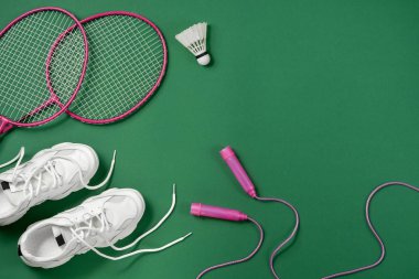 Spor düz mekiği ve badminton raket ile yatıyordu, halat atlama, yeşil arka planda spor ayakkabıları. Fitness, spor ve sağlıklı yaşam konsepti.