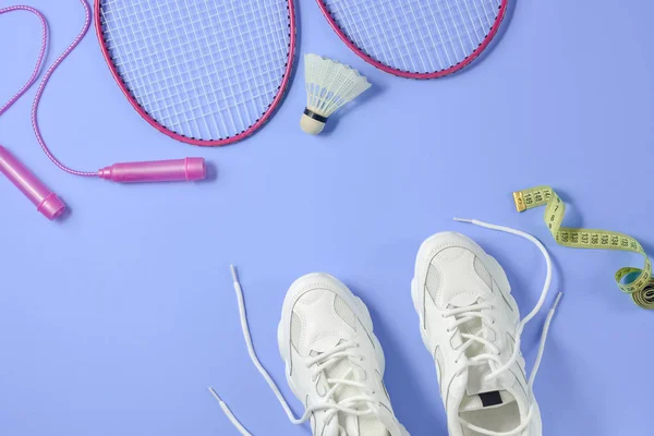 Sport flat lag met shuttle en badminton racket, springtouw, sneakers en meetlint op paarse achtergrond. Fitness, sport en gezond lifestyle concept. — Stockfoto