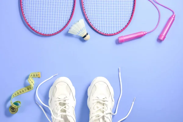 Sport uitrusting. Shuttle en badminton racket, springtouw, sneakers en meetlint op paarse achtergrond. Fitness, sport en gezond lifestyle concept. Platte lay, bovenaanzicht, kopieerruimte — Stockfoto