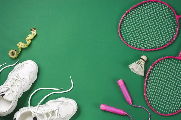 Sports flat lay with shuttlecock and badminton racket, skipping rope, sneakers and measuring tape on green background. Fitness, sport and healthy lifestyle concept. — Stock Photo, Image