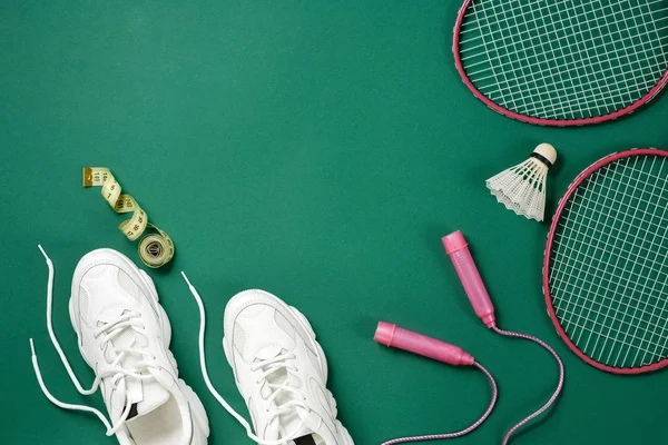Sportartikelen.. Shuttle en badminton racket, springtouw, sneakers en meetlint op groene achtergrond. Fitness, sport en gezond lifestyle concept. — Stockfoto