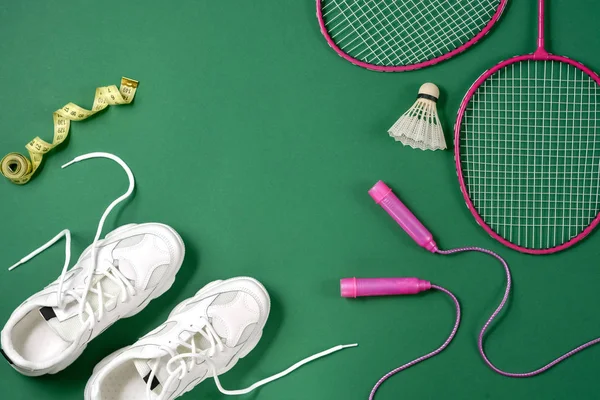 Sportartikelen.. Shuttle en badminton racket, springtouw, sneakers en meetlint op groene achtergrond. Fitness, sport en gezond lifestyle concept. — Stockfoto