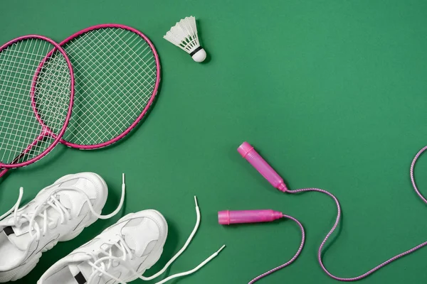 Sport flat lag met shuttle en badminton racket, springtouw, Sneakers op groene achtergrond. Fitness, sport en gezond lifestyle concept. — Stockfoto