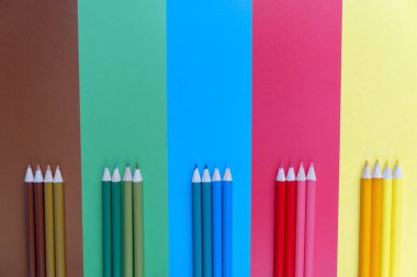 Yaratıcı düz mavi, kahverengi, yeşil, kırmızı ve sarı arka plan üzerinde renkli kalemler ile okul kavramı geri yatıyordu. Minimal konsept sanatı. Üst görünüm, kopyalama alanı.