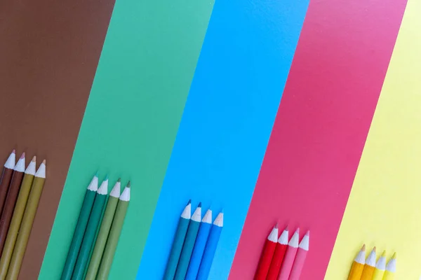 El plano creativo se remonta al concepto de la escuela con lápices de colores sobre fondo azul, marrón, verde, rojo y amarillo. Concepto de arte mínimo. Vista superior, espacio de copia . —  Fotos de Stock