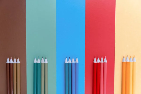 Skolan färgpennor på blå, brun, grön, röd och gul bakgrund. Minimal koncept konst. Creative Flat Lay, uppifrån, kopiera utrymme. — Stockfoto