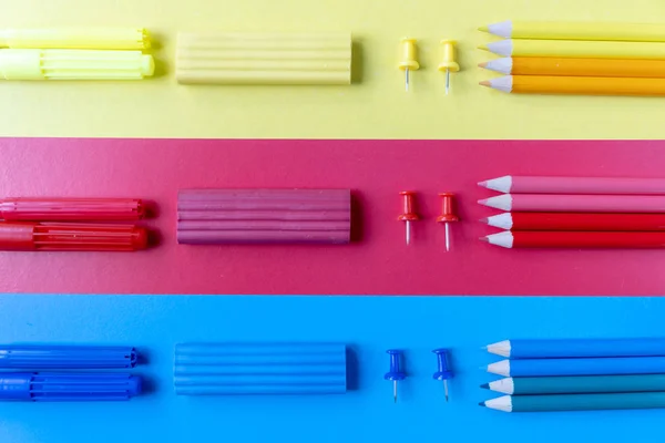 Concepto escolar con lápices de colores, plastilina y material de oficina sobre fondo azul, rojo y amarillo. Plano, vista superior, espacio para copiar . —  Fotos de Stock