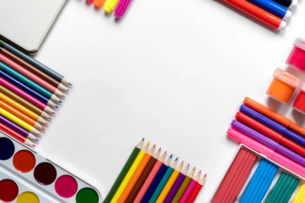 Вернемся к школьной концепции. Школьное оборудование с цветными карандашами, гуашью, акварелью, пластилином и блокнотом на белом фоне. Плоская кладка, вид сверху, копировальное пространство . — стоковое фото