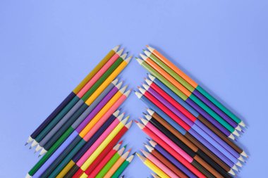 Okul konseptine geri dönelim. Mavi arka planda yalıtılmış birçok renkli kalemin yakın çekim görüntüleri. Düz döşeme, üst görünüm, kopyalama alanı.