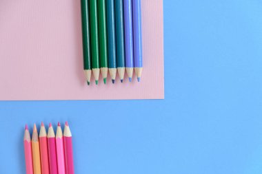 Yaratıcı düz mavi ve pembe arka plan üzerinde renkli kalemler ile okul kavramı geri yatıyordu. Minimal konsept sanatı. Üst görünüm, kopyalama alanı.