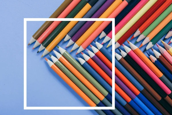 Σχολική ιδέα με χρωματιστά μολύβια σε μπλε φόντο με λευκό σκελετό. Δημιουργική επίπεδη θέση, κορυφή προβολή, αντίγραφο χώρου. — Φωτογραφία Αρχείου