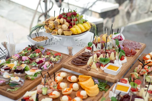 Grande variedade de alimentos com lanches frios, carne e saladas, frutas, carnes frias, queijo e geléia servidos. Variedade de deliciosos lanches saborosos na mesa . — Fotografia de Stock