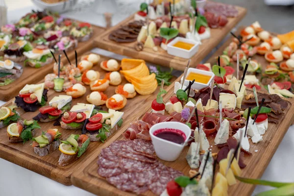 Grande variedade de alimentos com lanches frios, saladas, carnes frias, queijo e geléia servidos. Variedade de deliciosos lanches saborosos na mesa. Recepção de casamento — Fotografia de Stock