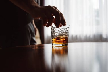 Elinde bir bardak viski olan adamın elini kapatın. Tatma ve degustation kavramı. Bir bardak viskiyle şık takım elbiseli işadamı. Metin için yer