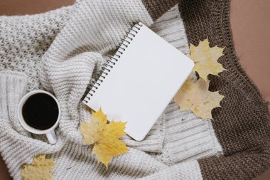 Sonbahar kompozisyon. Örme kazak, kahve, defter, kahverengi arka planda sonbahar akçaağaç yaprakları fincan. Düz yatıyordu, üst görünüm, kopya alanı.
