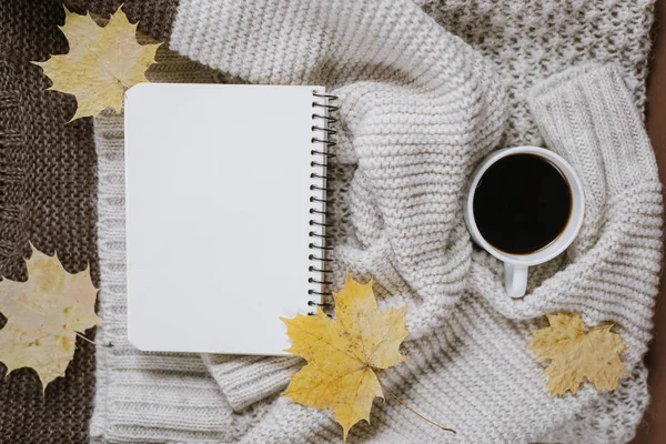 Herfst samenstelling. Gebreide trui, kopje koffie, notebook, herfst Maple bladeren op bruine achtergrond. Platte lay, bovenaanzicht, kopieer ruimte. — Stockfoto