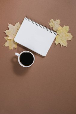 Sonbahar kompozisyon. Fincan kahve, defter, sonbahar akçaağaç yaprakları kahverengi arka plan. Düz yatıyordu, üst görünüm, kopya alanı.
