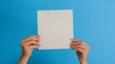 Vücut dili kavramı. Boş kağıt kağıdı yalıtılmış olarak tutan kadın elleri, kopya alanı yla mavi arka plan üzerinde onay veya anlaşma gösterir. El işareti. Jest gibi