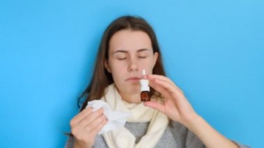 Hoşnutsuz genç kadının portresi burun aerosolkoklar, hasta hisseder, burun akıntısı vardır, burun tıkalı ilaç kullanır, doku tutar, üzgün yüz ifadesi vardır, gri bir kazak giyer. Sağlık