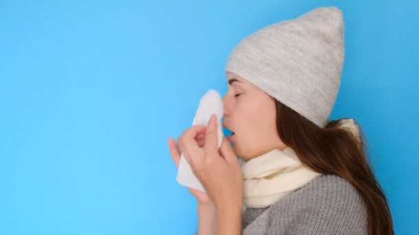 病发女吹流鼻涕得流感得感冒打喷嚏在蓝色空白工作室背景上隔离的组织 生病的女学生有花粉热过敏症状手帕 — 图库视频影像