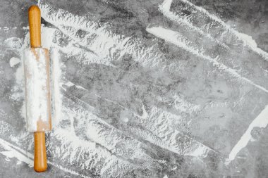 Gri bir arka plan üzerinde oklava ve beyaz un. Fırında menü, tarifi, ev yapımı pasta konsepti. Metin için boş alan. Düz döşeme, üst görünüm, metniniz için kopyalama alanı.