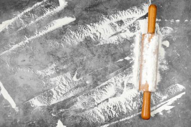 Pişirme düz oklava ile yatıyordu, gri arka plan üzerinde un. Fırında menü, tarifi, ev yapımı pasta konsepti. Metninizin kopya alanı yla üst görünüm.