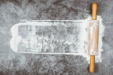 Pişirme düz oklava ile yatıyordu, gri arka plan üzerinde un. Fırında menü, tarifi, ev yapımı pasta konsepti. Metninizin kopya alanı yla üst görünüm.